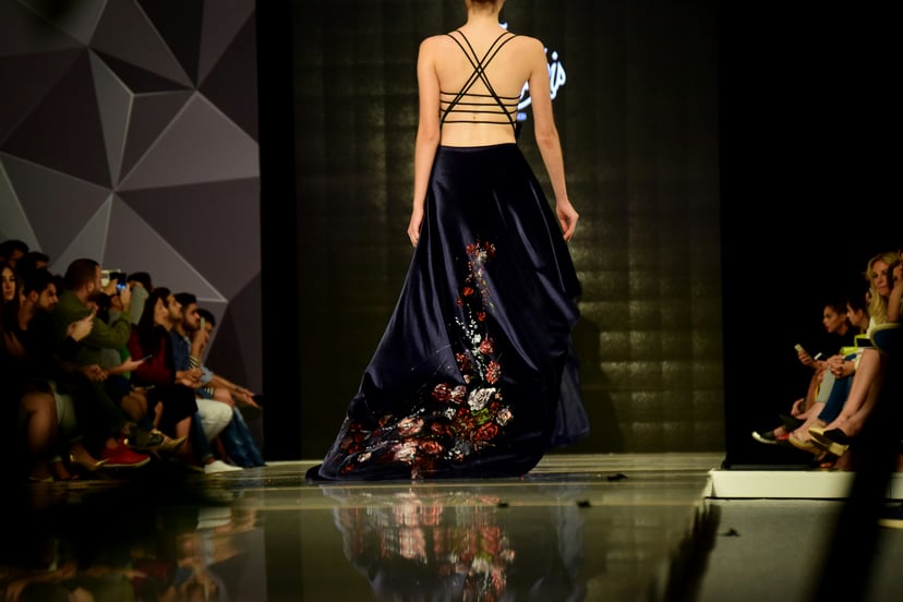 A model walking a fashion runway in a backless gown