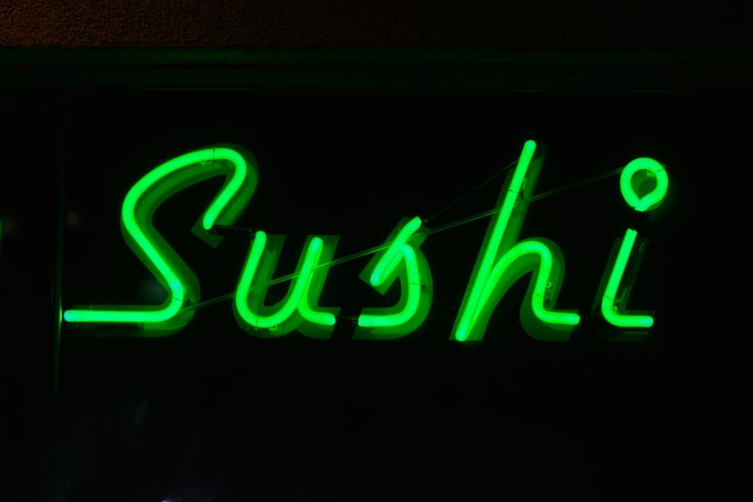 a green neon sign saying 'sushi'