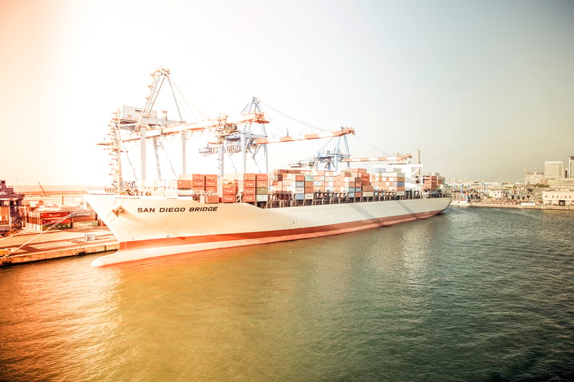 a cargo ship with the sun glowing on it