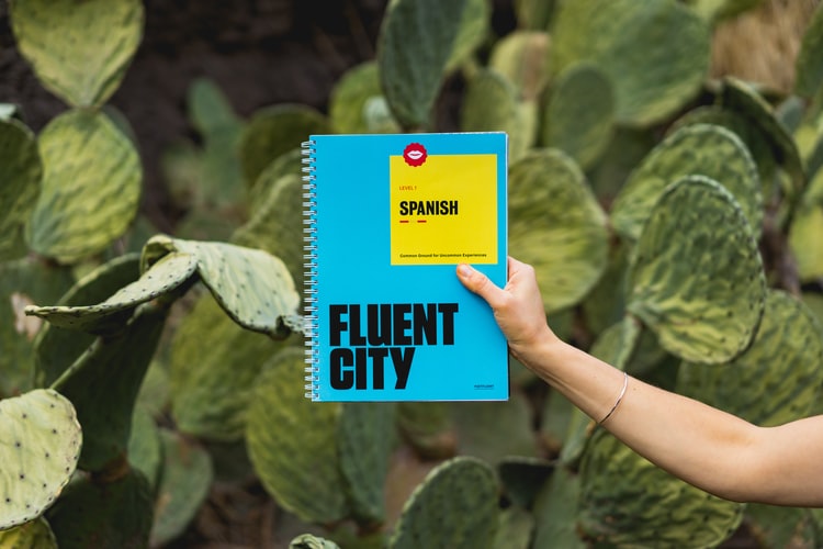 A hand holding a Spanish phrase book in front of cacti