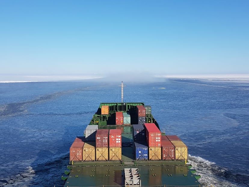 A view of shipping containers on the deck of a cargo ship as seen from the ship's bridge