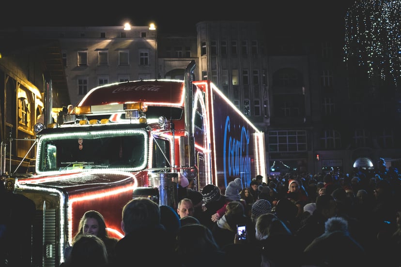 A Coca Cola Christmas truck surrounded by crowds