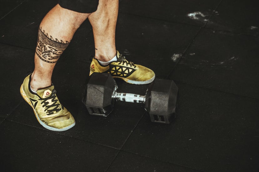 a man standing in front of a small dumbbell