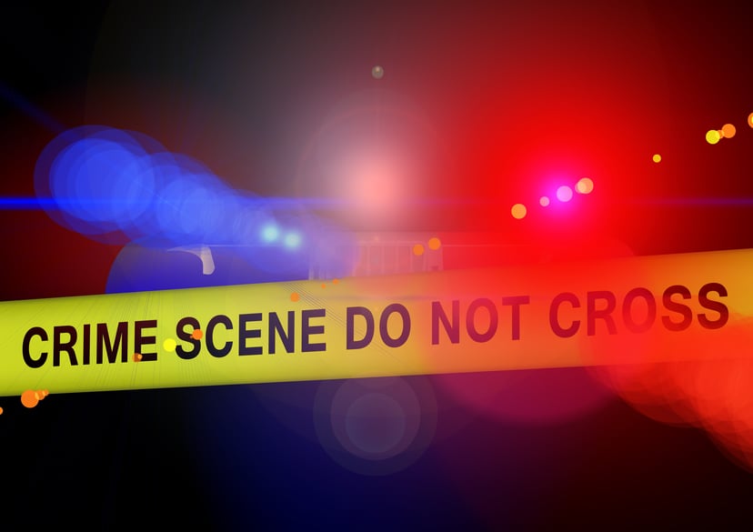 Yellow police crime scene tape and flashing emergency vehicle lights