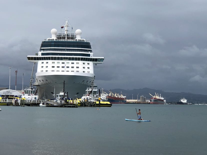 The Celebrity Solstice cruise ship in a port surrounded by much smaller boats