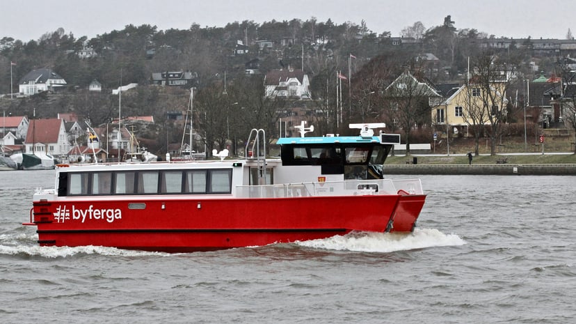a small red electrically-powered ferry on a river in Norway