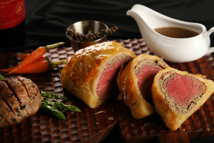 Beef Wellington and a jug of gravy on a serving platter