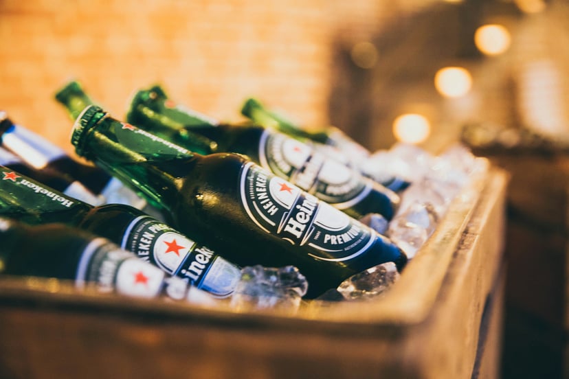 Bottles of Heineken beer resting on ice in a wooden crate