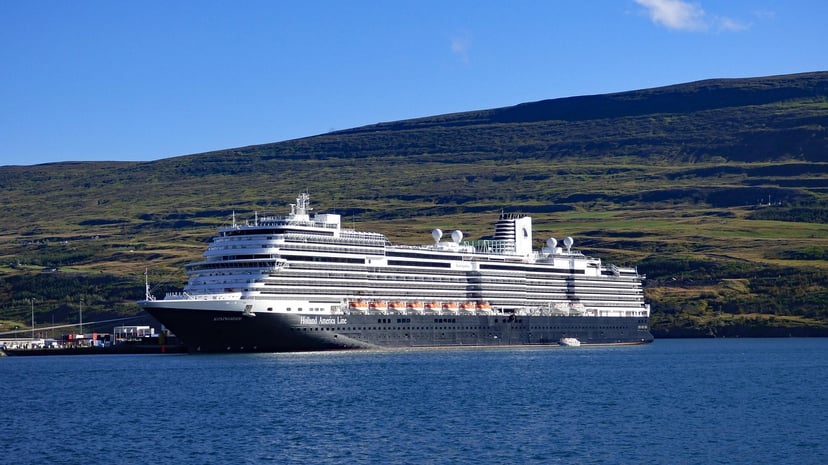 The Holland America cruise ship Koningsdam moored near land under a blue sky