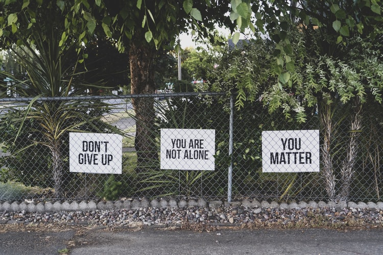 3 motivational signs on a chain link fence