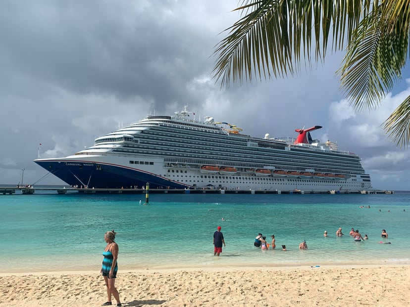 The Carnival Magic cruise ship sailing past a tropical shoreline