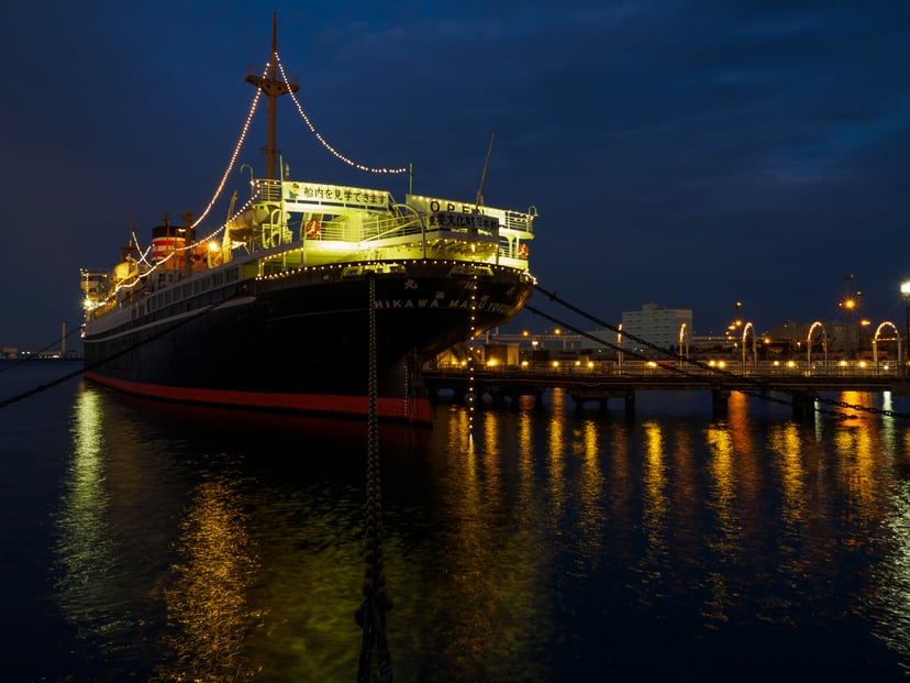 a ship in port at night with the mooring lines visible at the front of the bow