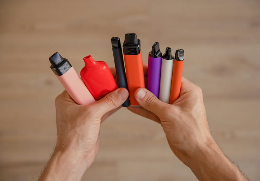 Hands holding a selection of vapes