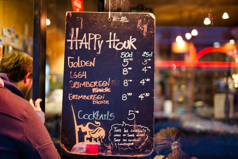 a chalkboard in a bar advertising happy hour