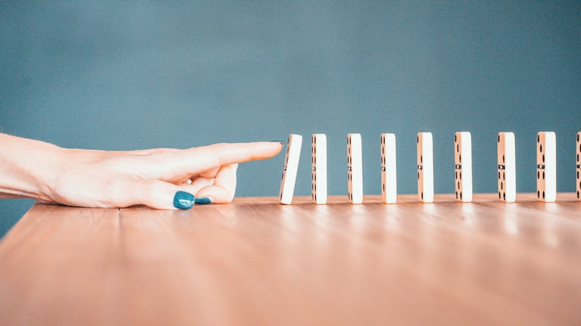 A finger pushing a line of dominos over
