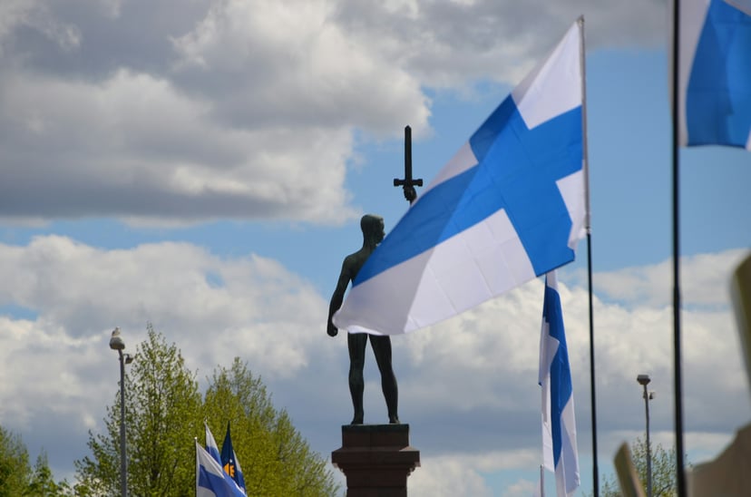 The Finnish flag flying in front of a warrior statue