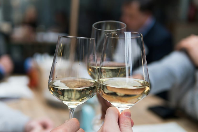 People clinking three glasses of white wine