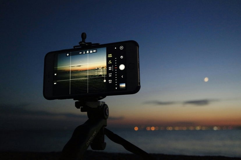 A view of the ocean at night through a smartphone's camera set up on a tripod