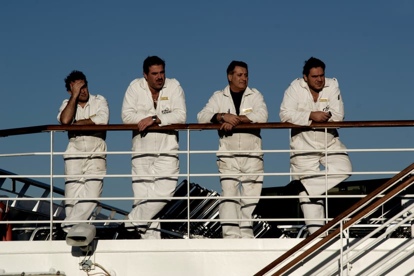 Four seafarers leaning on the rail of a ship while working in deckhand jobs