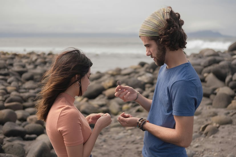 a couple on a beach inspecting something they've found