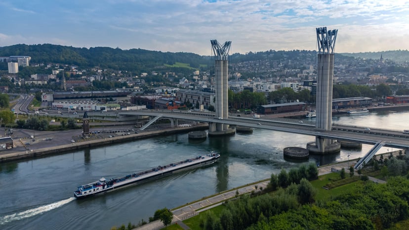 A boat on the River Seine passing under a bridge in Rouen, France