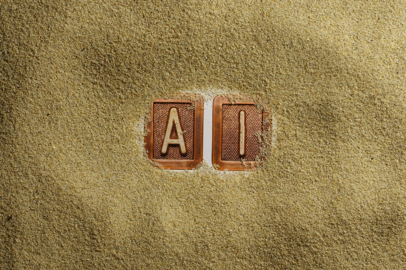 The letters A and I surrounded by sand