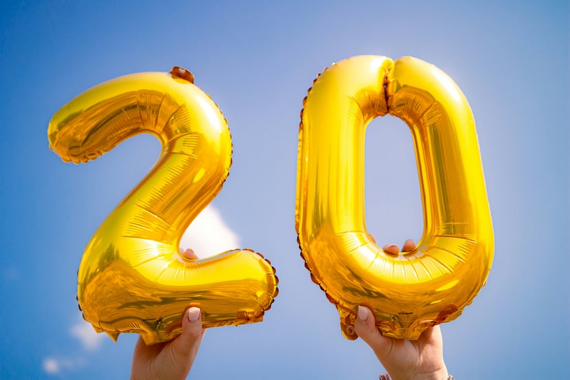 Hands holding up gold 2 and 0 balloons