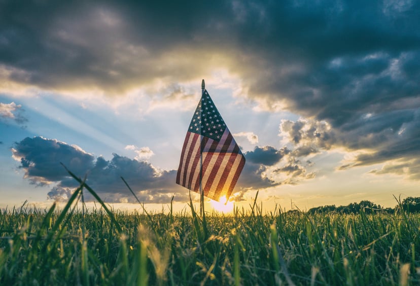 The Stars and Stripes planted in a field at sunset