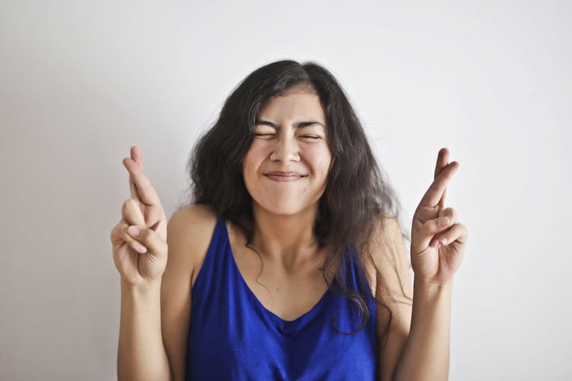 Woman with her eyes squeezed shut and her fingers crossed