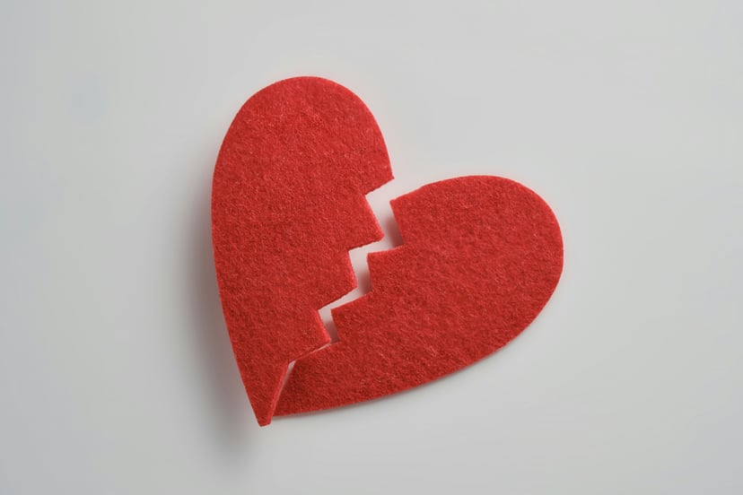 A red felt broken heart on a white background