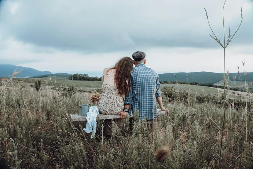 A couple sitting on a bench looking out over fields