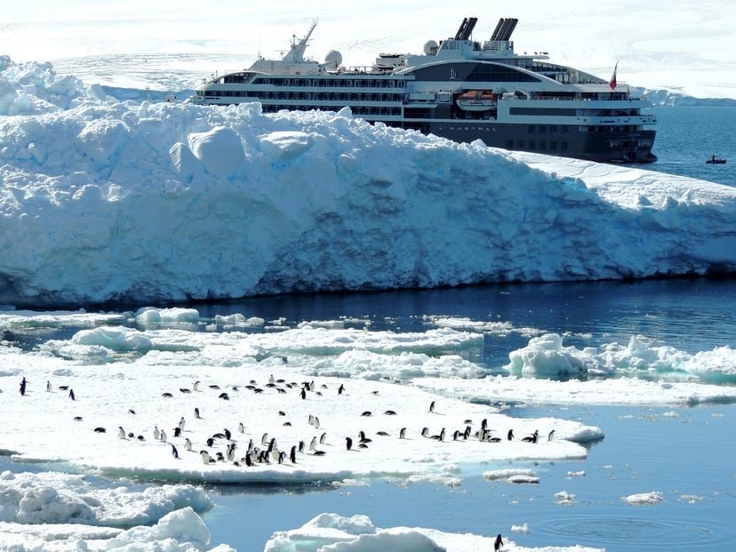 The Le Commandant Charcot exploration cruise ship sailing past an icy bank