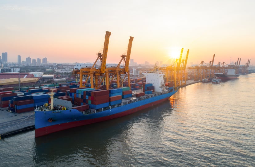a container ship being loaded or unloaded in a port at sunset