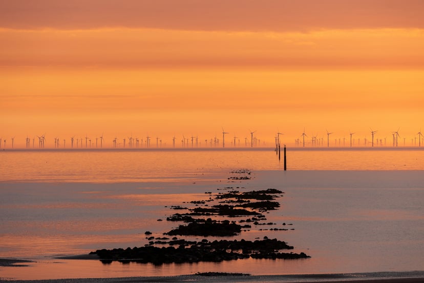 An offshore windfarm at sunset