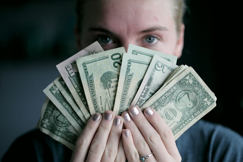 A person holding a fan of bank notes