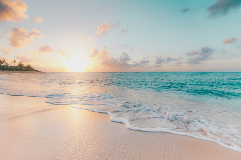 the ocean lapping a sandy beach at sunset
