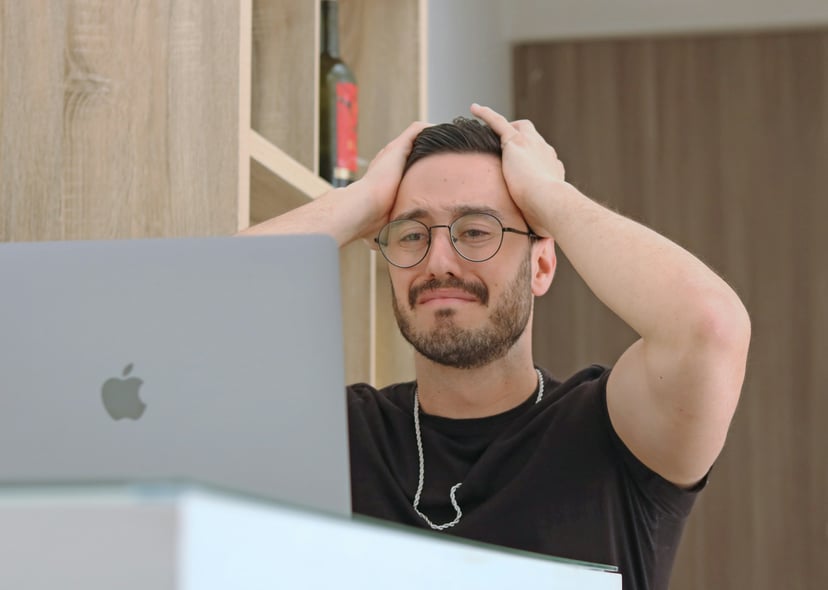 Man holding his head while looking at his laptop