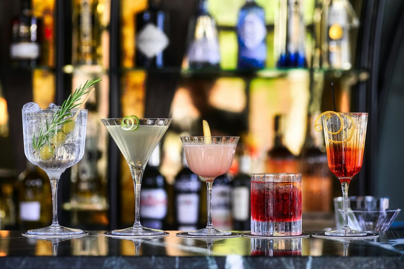 A range of different cocktails sitting on a bar