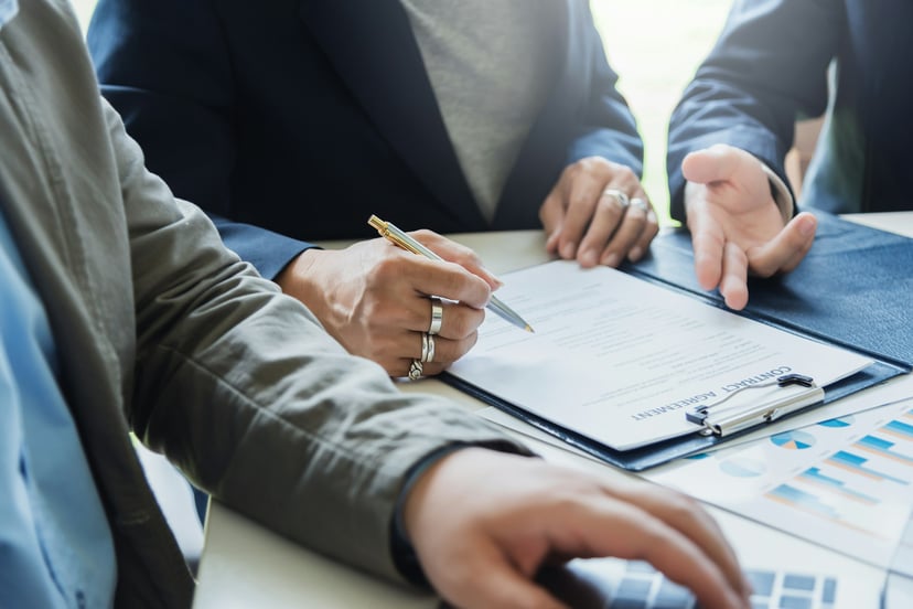 People in business suits looking at documents on a clipboard