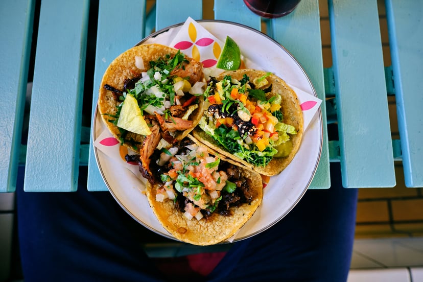 Tacos on a plate on a blue wooden picnic style table