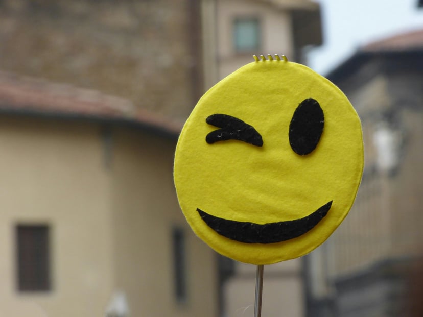 a yellow emoji style face winking