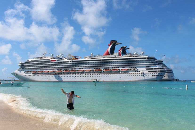 The Carnival Conquest cruise ship moored off a tropical beach