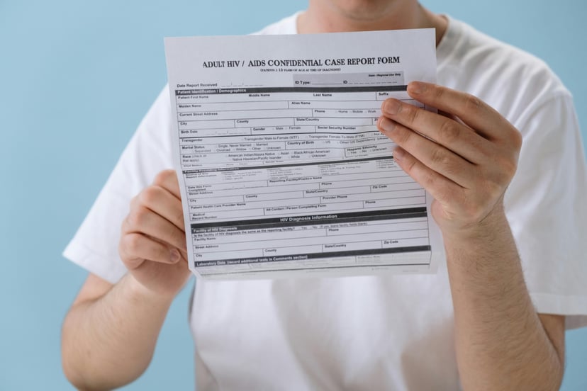 A man in a white t-shirt holding an HIV certificate