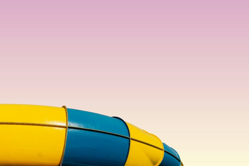A yellow and blue waterslide against a pink sky