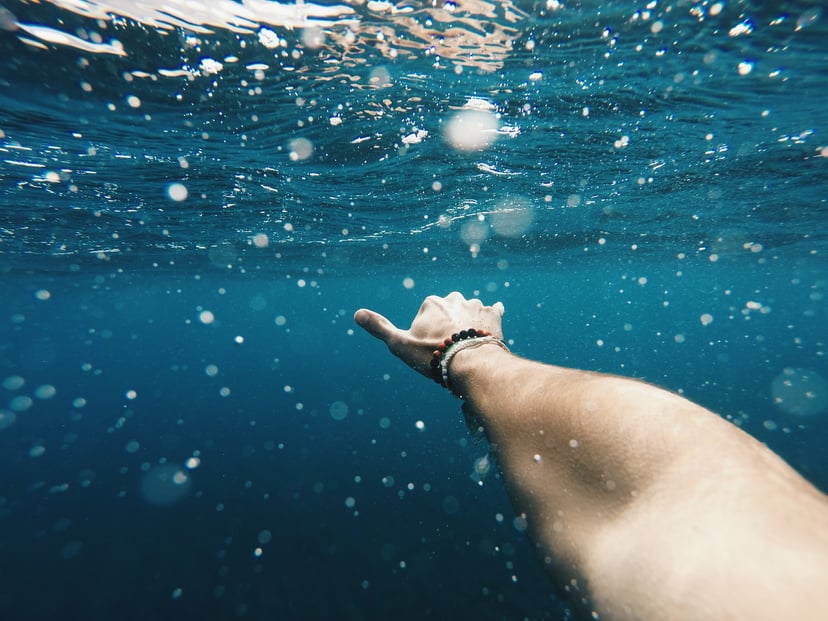 person reaching out under the sea