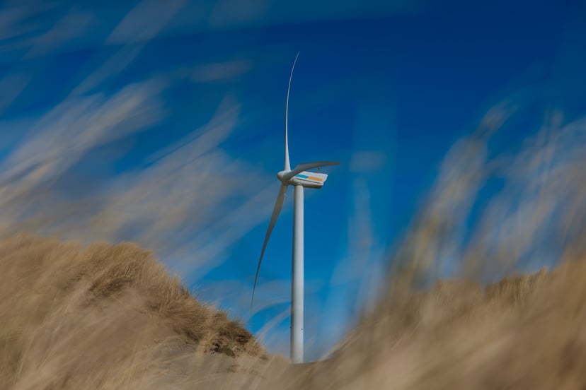 A wind turbine behind sand dunes