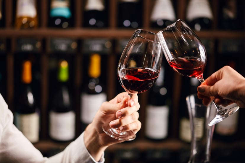 Two people clinking glasses of red wine together