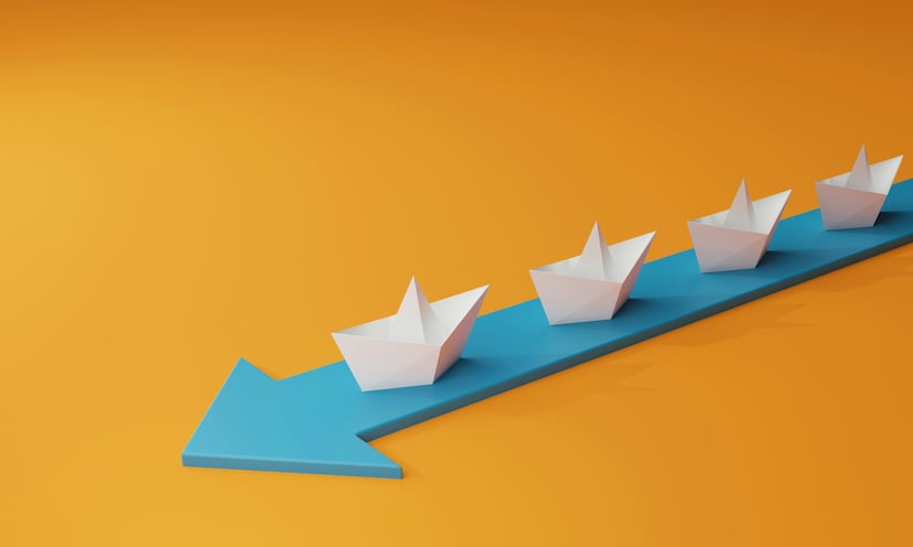 Four paper boats on a forward pointing arrow