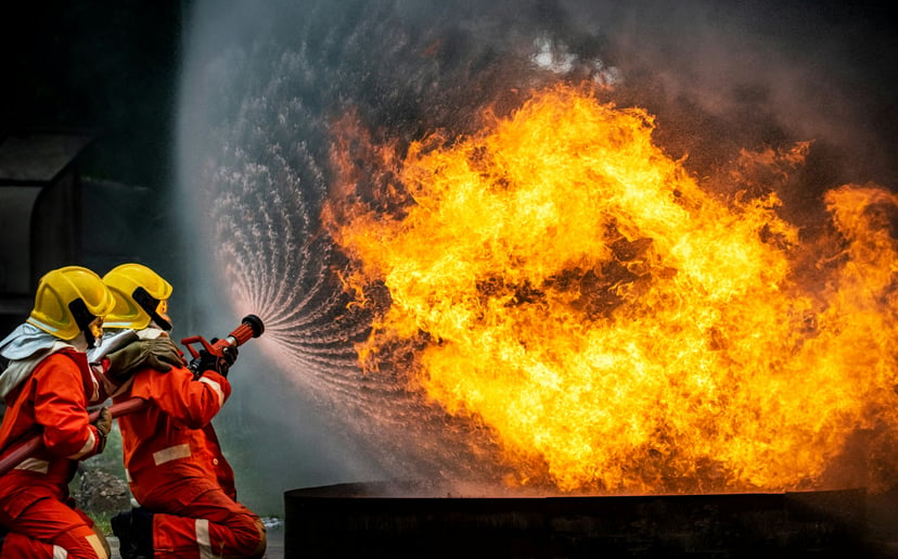 Firefighters using a high pressure water hose on an inferno