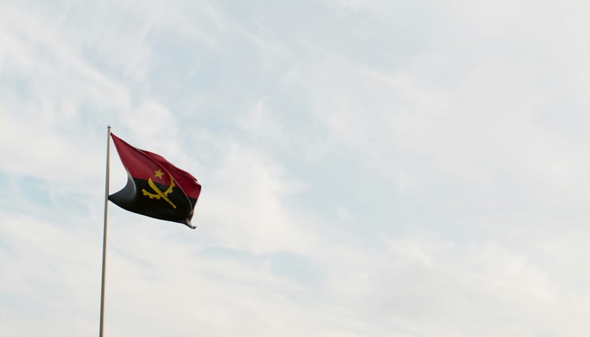 The flag of Angola flying against a cloudy sky